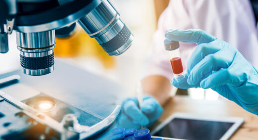 Researcher holding blood sample under a microscope.